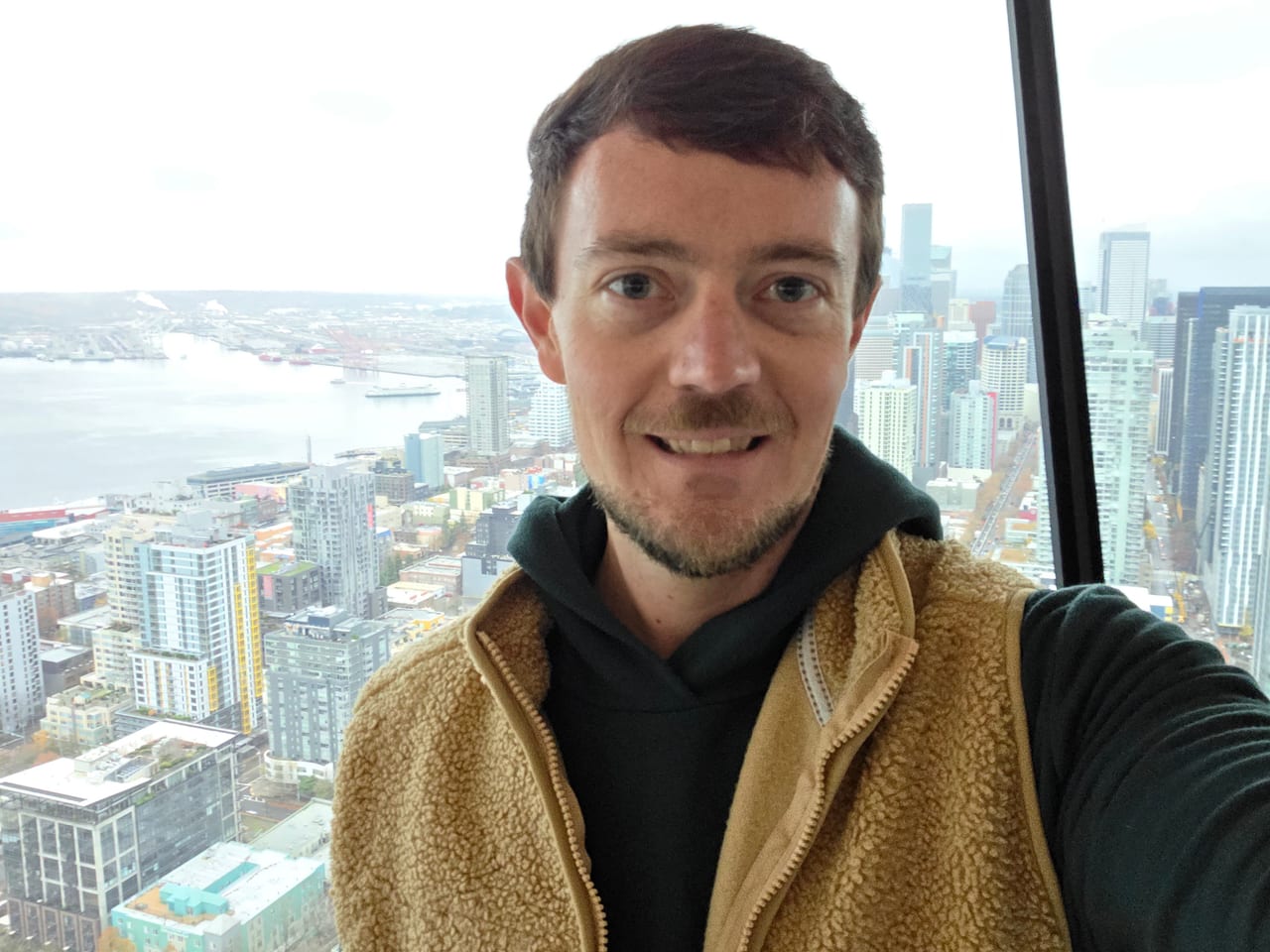 Tyler smiling, with the Seattle skyline and waterfront far below.
